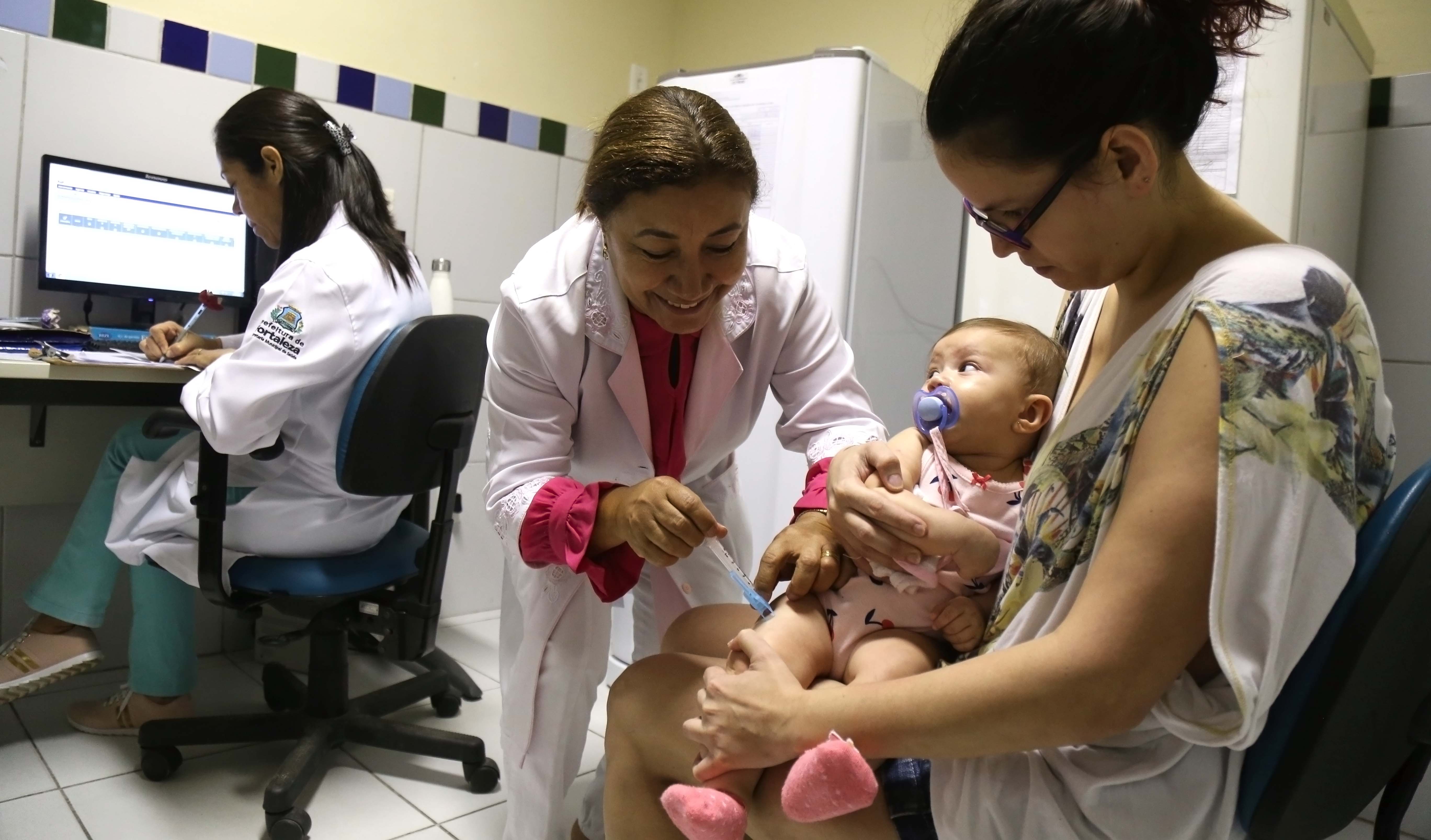 enfermeira vacina um bebê que está no colo da mãe